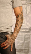 male arm in grey shirt with henna tattoo on arms and fingers